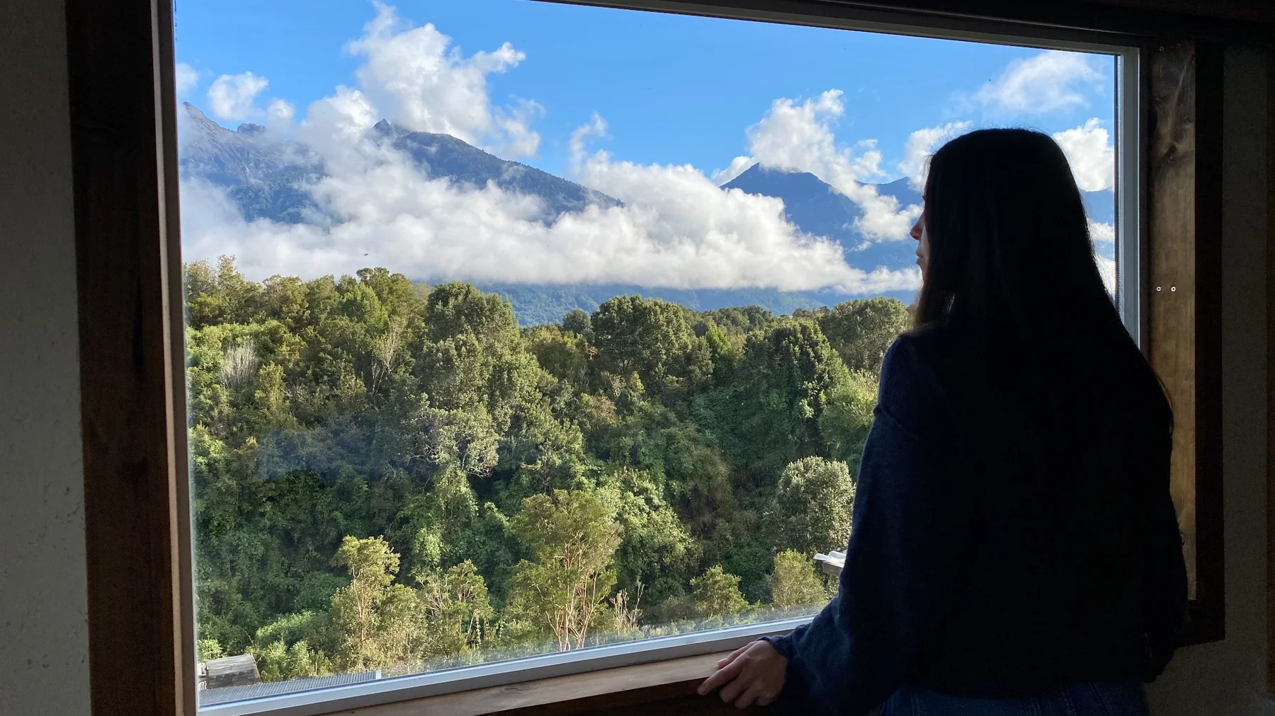 Persona contemplando las montañas desde una gran ventana